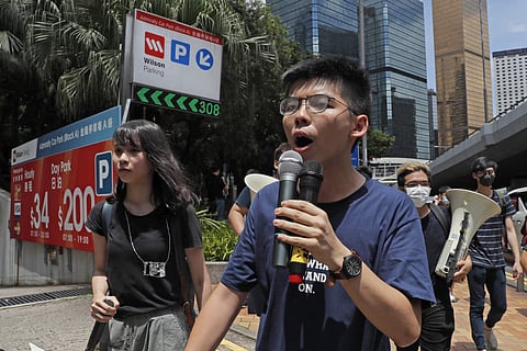 Pro-democracy activist Joshua Wong, center left, speaks as protesters surround the police headquarters in Hong Kong. | ( File Photo | AP )