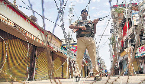 CRPF personnel stand guard during restrictions at Raghunath Bazar in Jammu on Monday. Kashmiri Pandits living there celebrated the Centre’s decision | Pti