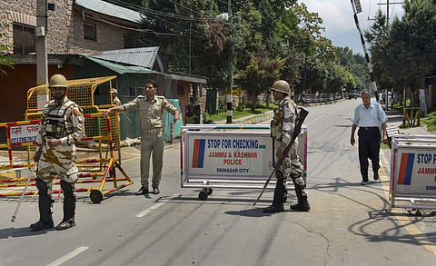 Security personnel stand guard as they block a road leading to the residence of Farooq Abdullah Omar Abdullah and Mehbooba Mufti during restrictions in Srinagar Thursday August 8 2019. | PTI
