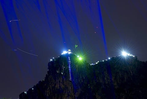 Demonstrators hold up the mobile phone lights and laser pointer as they gather on the Lion Rock mountain against the night view of Hong Kong. ( Photo | AP )