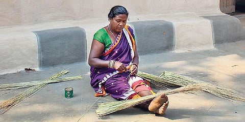 A woman ties hill grass for making brooms in Mundapada village I Express