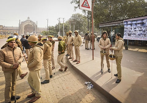 Police personnel stand guard beside a poster of protestors suspected to have incited vandalism during protests against CAA and NRC in Lucknow. (File | PTI)