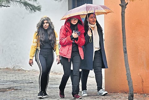 Commuters take cover under an umbrella on an overcast Tuesday. (Photo | EPS/PARVEEN NEGI)