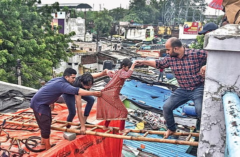 A man helps others cross onto another building in Chaderghat | VINAY MADAPU
