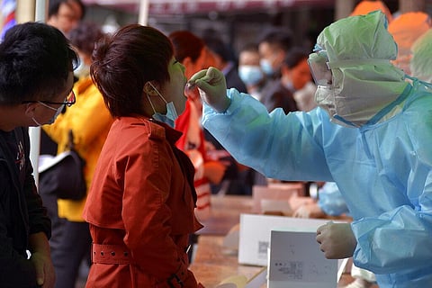 A medical staff takes a swab from a woman as residents line up for the COVID-19 test near the residential area in China. (Photo | AP)