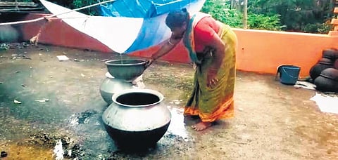 Pramila Majhi of Koladiha village collects rainwater in an utensil on the roof of her house.