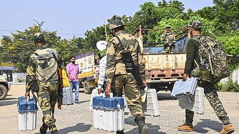 Security personnel carrying EVMs on their way to a polling booth.