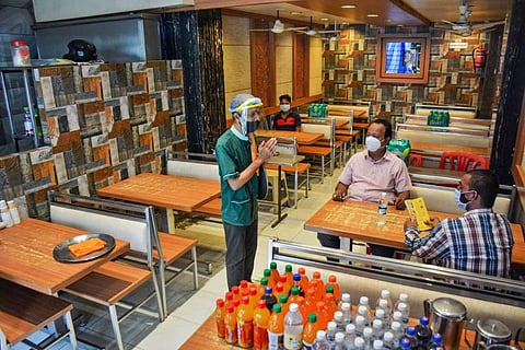 A staff member greets customers at a restaurant after it reopened during Unlock 5 amid the coronavirus pandemic in Thane Monday. (Photo | PTI)