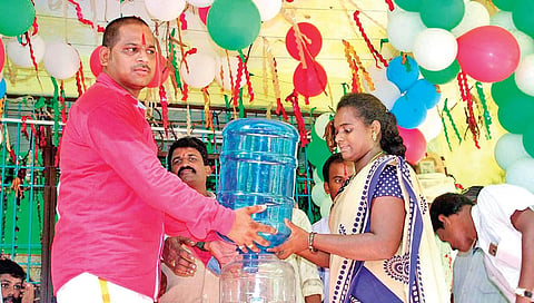 Pullata Ram Kumar distributing a water can to a woman at Bairipuram in Srikakulam district. (File photo| EPS)
