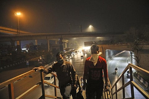 Pedestrians walk on an overbridge on a street covered with smog in New Delhi. (Photo | AP)