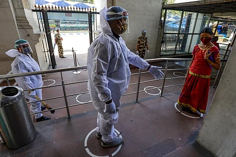 A security guard in protective suit and face shield gestures to a visitor at the entrance of the Indian Museum, that reopened for public Tuesday. (Photo | AP)
