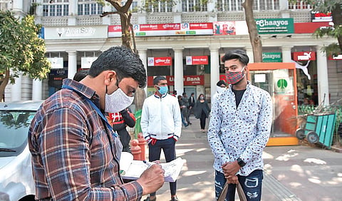 A civil defence personnel challans a man found not wearing a mask in New Delhi. (Photo | Shekhar Yadav, EPS)