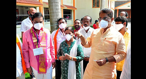 BJP candidate for RR Nagar Munirathna with Minister R Ashoka and his wife outside a polling booth in Bengaluru, on Tuesday | Express