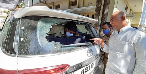 Police personnel inspect the damaged car of BJP corporator Lachi Reddy