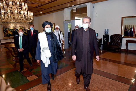 Pakistan Foreign Minister Shah Mahmood Qureshi, right, and Mullah Abdul Ghani Baradar, head of a Taliban political team, arrive at the Foreign Ministry. (Photo | AP)