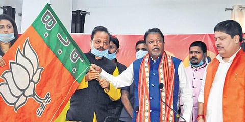 BJP national vice president Mukul Roy (2R) handovers the party flag to former TMC leaders S K Harun Rashid (2L) and Sultana Begum (L) after they joined the party, in Kolkata on Friday.