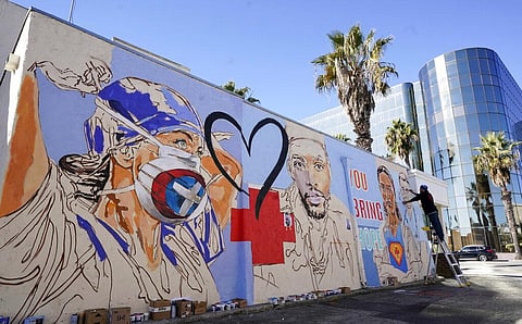 Artist Samir Arghandwall, also known as Samir Evol, works on a mural honoring health care workers on the front lines of the COVID-19 pandemic, Monday, Dec. 21 in California. (Photo | AP)