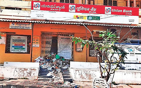Sanitation workers of Vuyyuru Nagar Panchayat staged a demonstration by dumping waste before a bank branch for delay in sanctioning loans. (Photo | EPS)