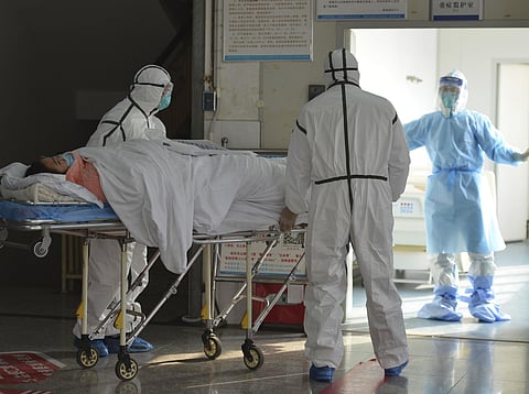 Medical workers in protective suits move a coronavirus patient into an isolation ward.(File Photo | AP)