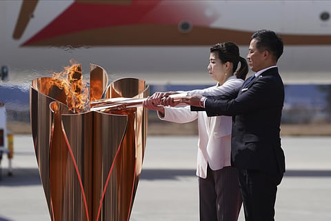 Three-time Olympic gold medalists Tadahiro Nomura, right, and Saori Yoshida light the torch during Olympic Flame Arrival Ceremony at Japan Air Self-Defense Force Matsushima Base in Higashimatsushima in Miyagi Prefecture, north of Tokyo, Friday, March 20,