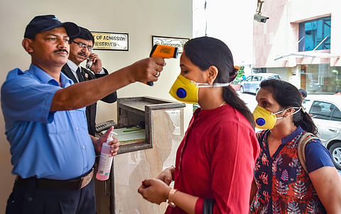An official uses thermal screening device on visitors in the wake of coronavirus pandemic. (Photo | PTI)