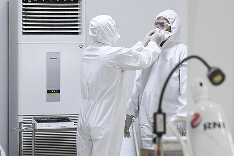 A staff member assists a colleague to don his protective gears at an emergency hospital set up amid the new coronavirus outbreak in Jakarta, Indonesia, Monday, March 23, 2020. (Photo | AP)