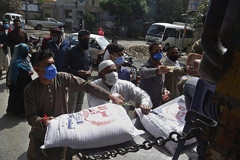 People buy wheat flour from a governmental subsidized sale point during lockdown, in Lahore, Pakistan. (Photo | AP)