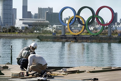 Men work at a construction site with the Olympic rings in the background Tuesday, March 3, 2020, at Tokyo's Odaiba district. (Photo | AP)
