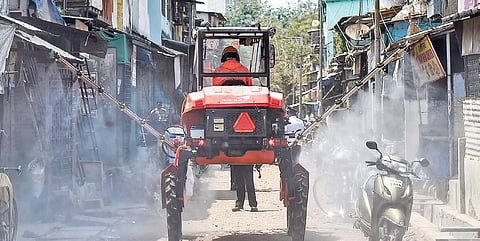 A firefighter decontaminates a road using a boom sprayer at Dharavi in Mumbai on Sunday | PTI