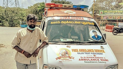 Manikandan standing beside his ambulance