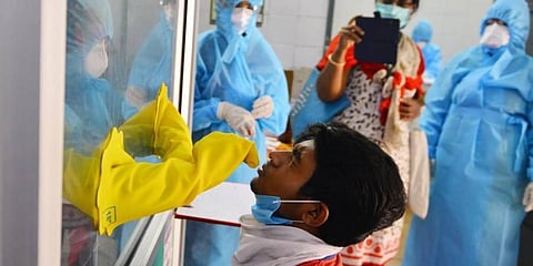 Health workers take nasal swabs from a person through a Covid-19 sample collection kiosk. (Photo | Debdatta Mallick, EPS)