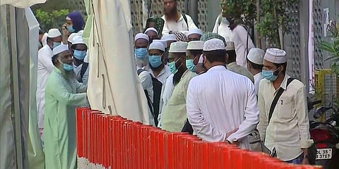 People from Markaz building wear a protective mask as they walk to board bus to hospital. (Photo| ANI)