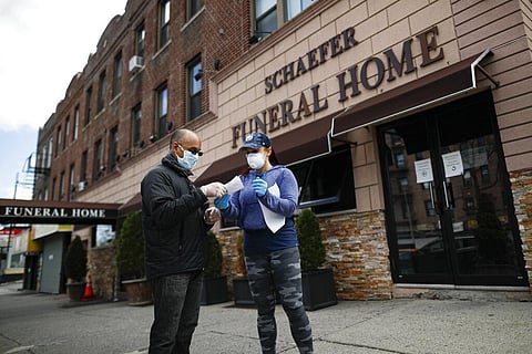 Employee Gina Hansen, right, hands documentation to a client outside Daniel J. Schaefer Funeral Home Thursday, April 2, 2020, in the Brooklyn borough of New York. The company is equipped to handle 40-60 cases at a time. But amid the coronavirus pandemic,
