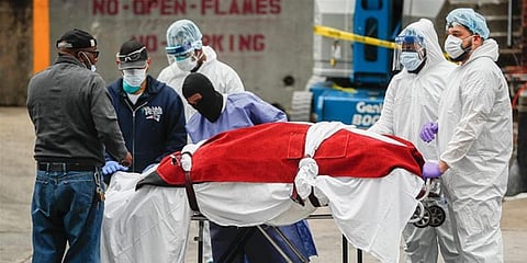 A body wrapped in plastic that was unloaded from a refrigerated truck is handled by medical workers wearing personal protective equipment at Brooklyn Hospital Center in New York City. (Photo | AP)