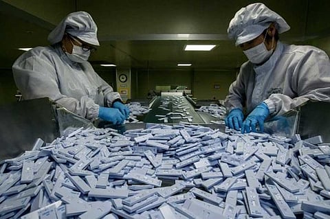 Sample testing devices used in diagnosing the COVID-19 novel coronavirus are checked on a production line as they are prepared to be included in testing kits for shipment at the SD Biosensor bio-diagnostic company near Cheongju, south of Seoul on March 27