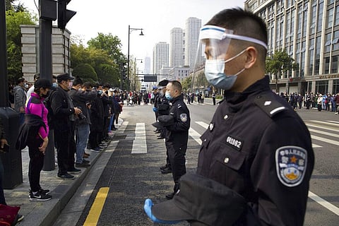 People and policemen bow their heads during a national moment of mourning for victims of coronavirus in Wuhan.(Photo | AP)