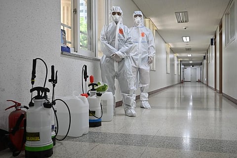 Health officials wearing protective gear prepare to spray disinfectant in a classroom in South Korea. (Photo| AFP)