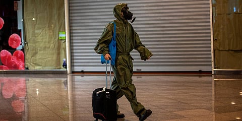 A passenger wearing a gas mask and a full protective suit arrives from London at the Barcelona airport. (Photo| AP)