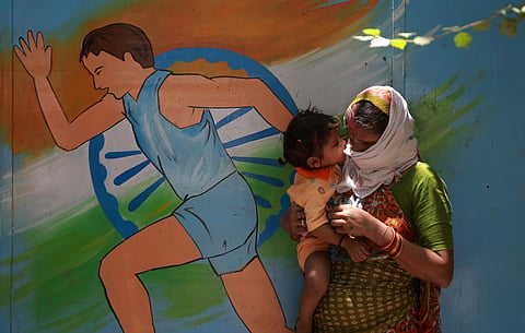 A migrant holds her child as she wait in a queue to register for a special train to go back home. (Photo | Shekhar Yadav, EPS)