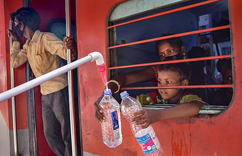 Cadets of Scouts Guides provide drinking water to the migrants sitting in a Shramik Special train for their native places during ongoing COVID-19 lockdown at Mathura Railway Station Thursday May 28 2020. (Photo | PTI)