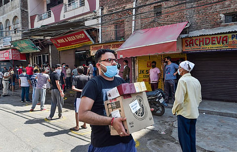 A customer carries alcohol after purchasing from a wine shop during the ongoing COVID-19 nationwide lockdown. (Photo | PTI)