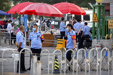Chinese police stand outside the entrance to a building holding a beef and lamb market in Beijing that was closed by authorities after it was visited by a person who tested positive for COVID-19, Friday, June 12, 2020. (Photo | AP)