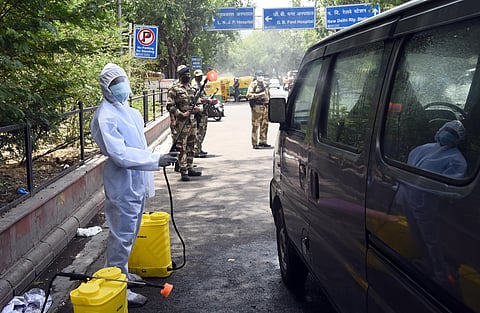 Workers clad in PPE disinfecting vehicles. (File Photo |Parveen Negi, EPS)