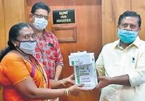 Mini L, principal of BTC, handing over the automatic sanitiser dispenser to U Rajeev, private secretary of Labour Minister T P Ramakrishnan