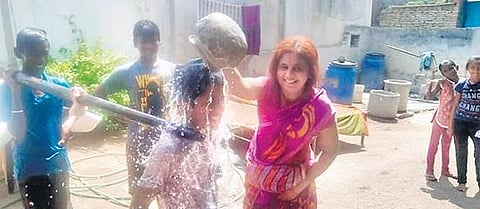A local resident of Bheempur village in Adilabad pours water on children carrying frogs tied to a bamboo, seeking the blessings of the rain god, as per their belief. (Photo| EPS)