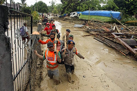 Rescuers wade through mud as they carry the body of a victim at an area affected by flash flood in Baebunta, South Sulawesi province, Indonesia (Photo | AP)