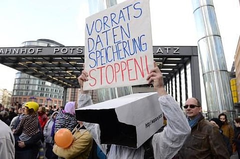 A demonstrator wearing a surveillance-camera shaped box on the head holds up a poster reading 'stop data preservation' as he attends a protest against the proposed US-EU free trade pact or Transatlantic Trade and Investment Partnership in Berlin on April