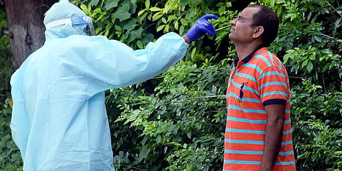 A health worker wearing PPE kit collects the swab sample of a man for COVID-19 test at a collection centre, during the lockdown, in Patna. (File photo| ANI)
