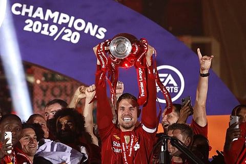Liverpool's English midfielder Jordan Henderson (C) lifts the Premier League trophy with his team-mates. (Photo | AFP)