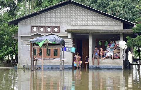 Villagers sit on a higher platform following flooding in their locality due to monsoon rain, at Baghmari village in Nagaon district. (File Photo | PTI)